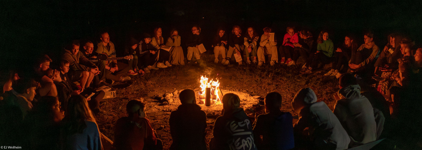 Konfis sitzen um ein Lagerfeuer